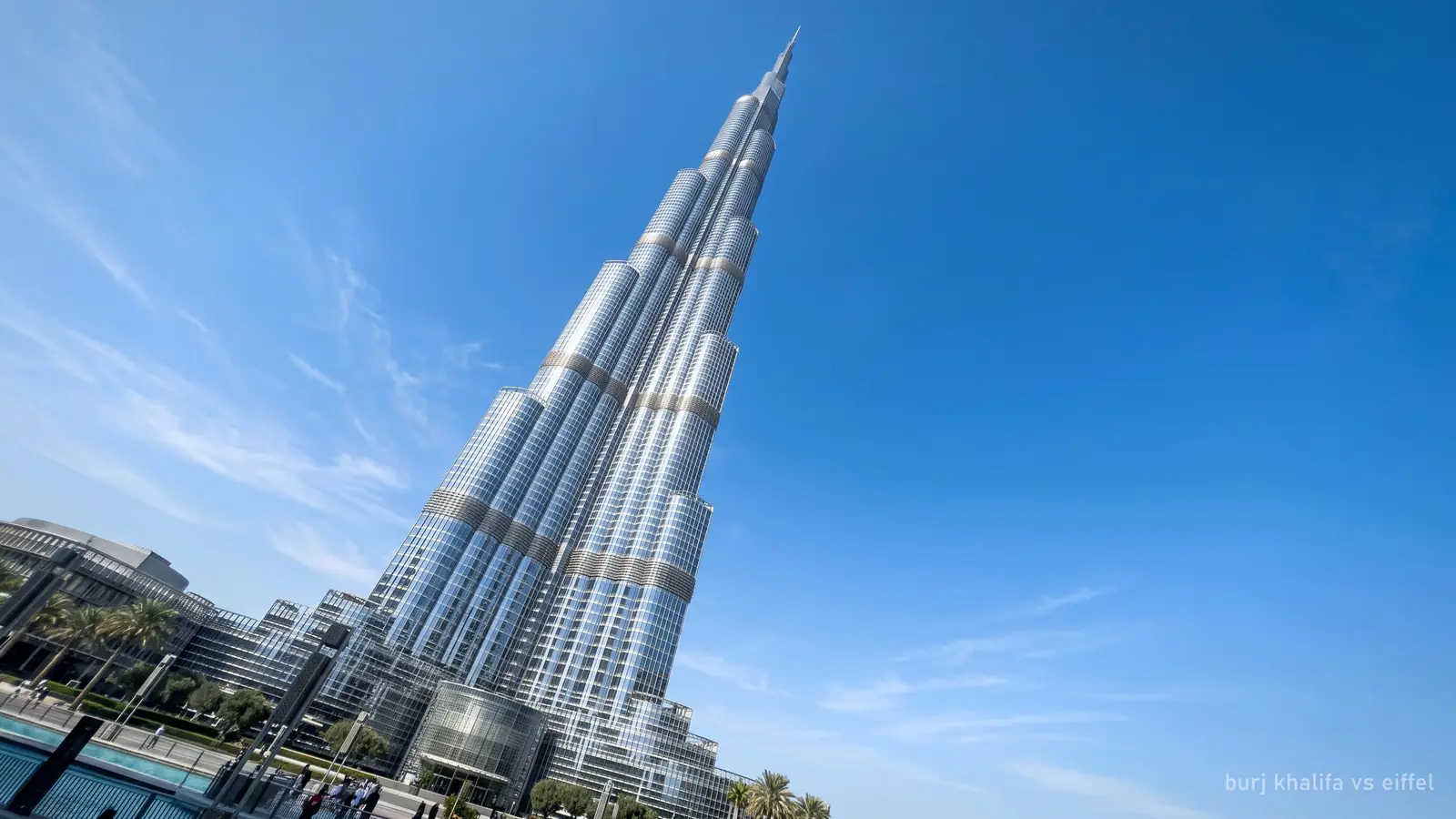 The slender stepped spire of the Burj Khalifa against a clear blue sky, seen from its base looking up (generated illustration)
